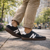 Zancada con zapatillas barefoot hombre negras resaltando la flexibilidad y estilo retro.